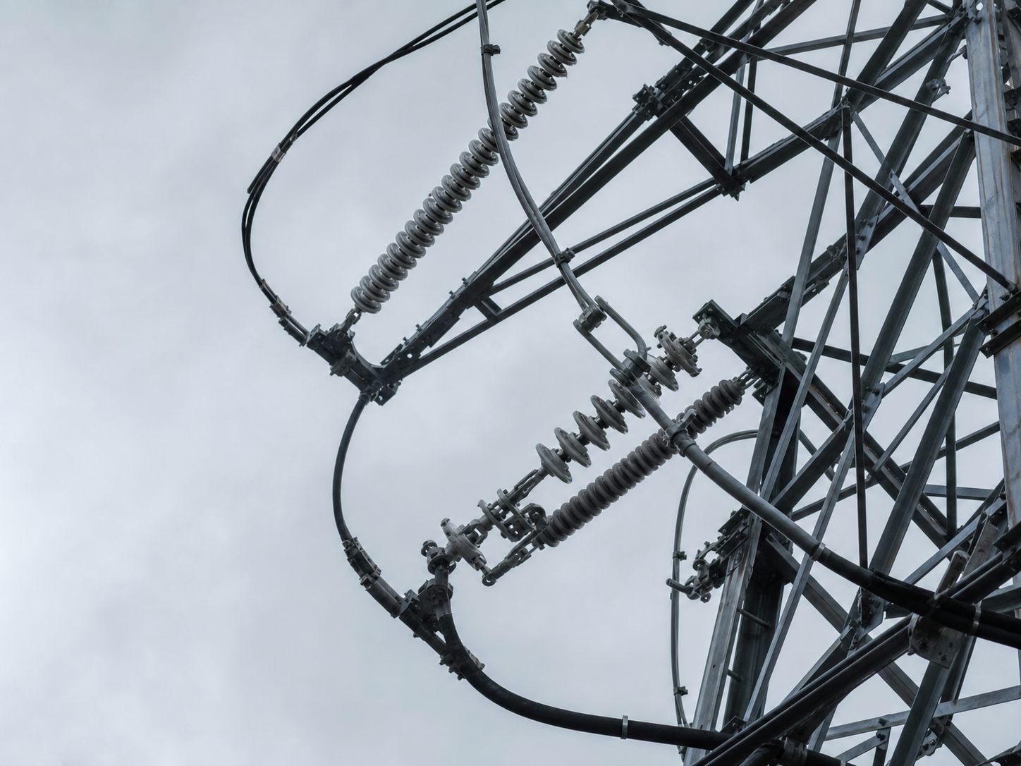 曇天の送電設備と架線金具を見上げる構図